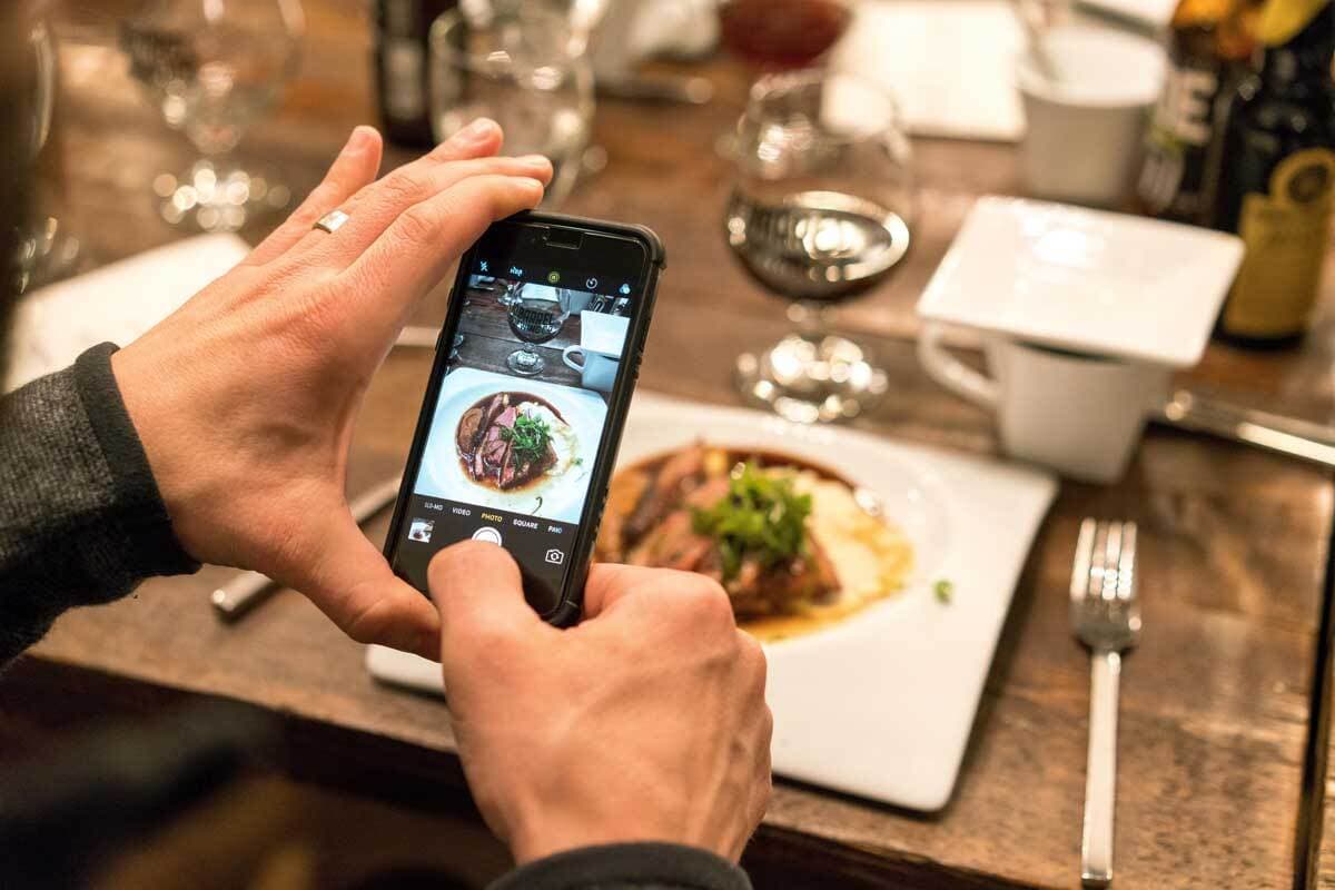 Person photographing plated dish with smartphone.