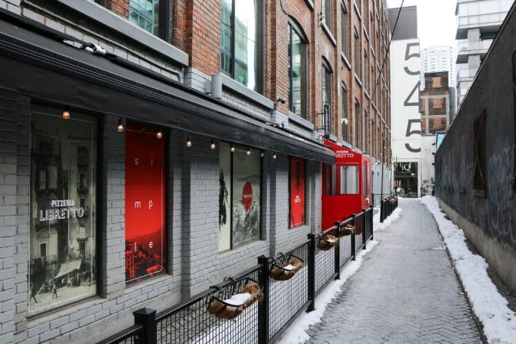 Urban alley with building and restaurant signs.