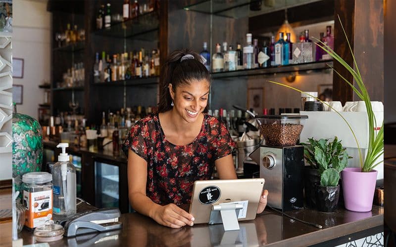 Barista using tablet in coffee shop.