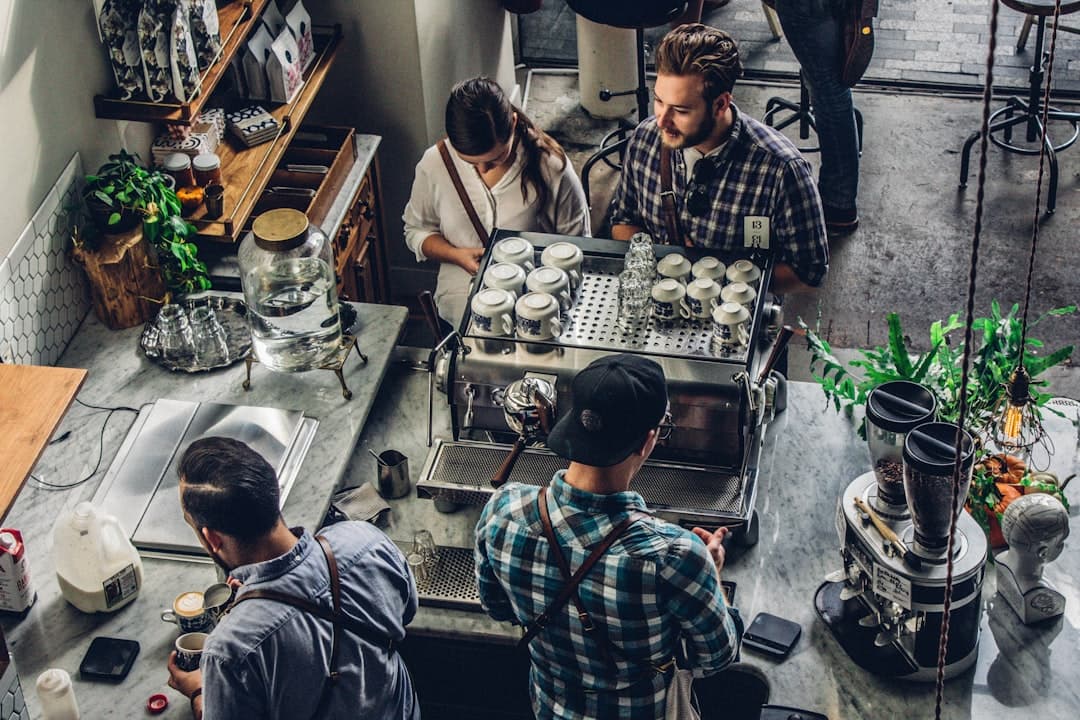 Baristas preparing coffee in busy cafe.
