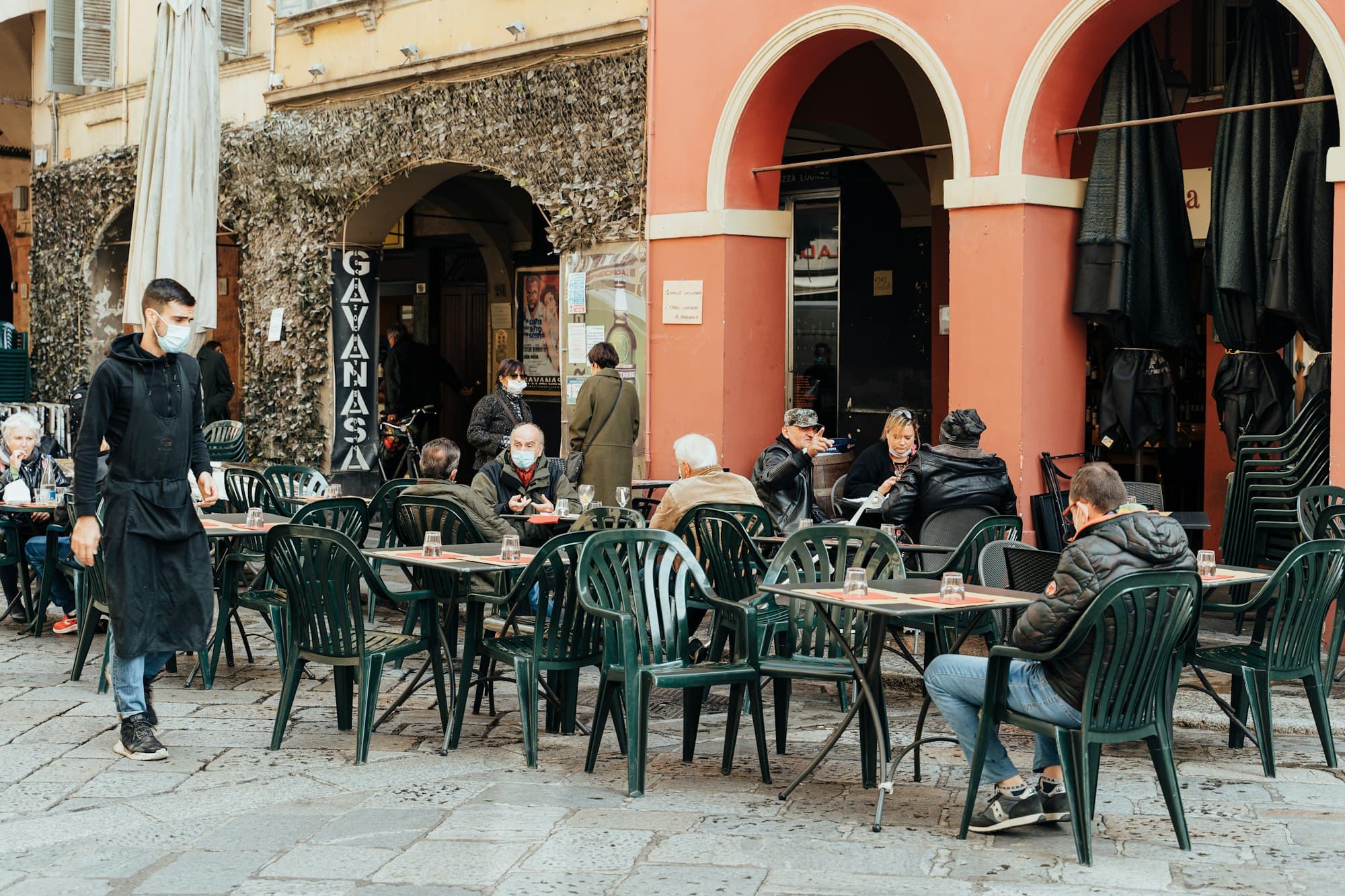 People dining outside a cafe with arched architecture.
