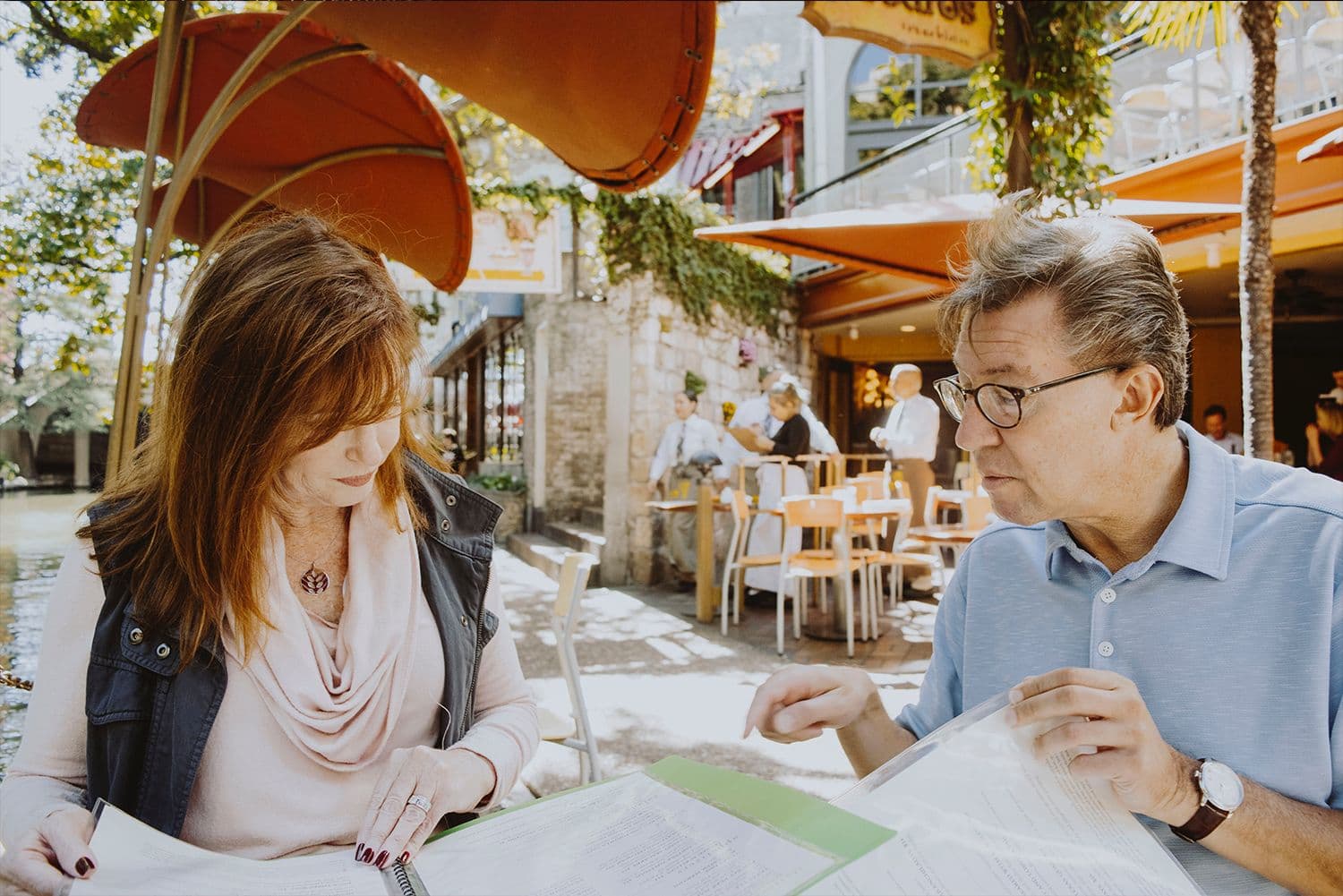People reviewing menus at outdoor restaurant.