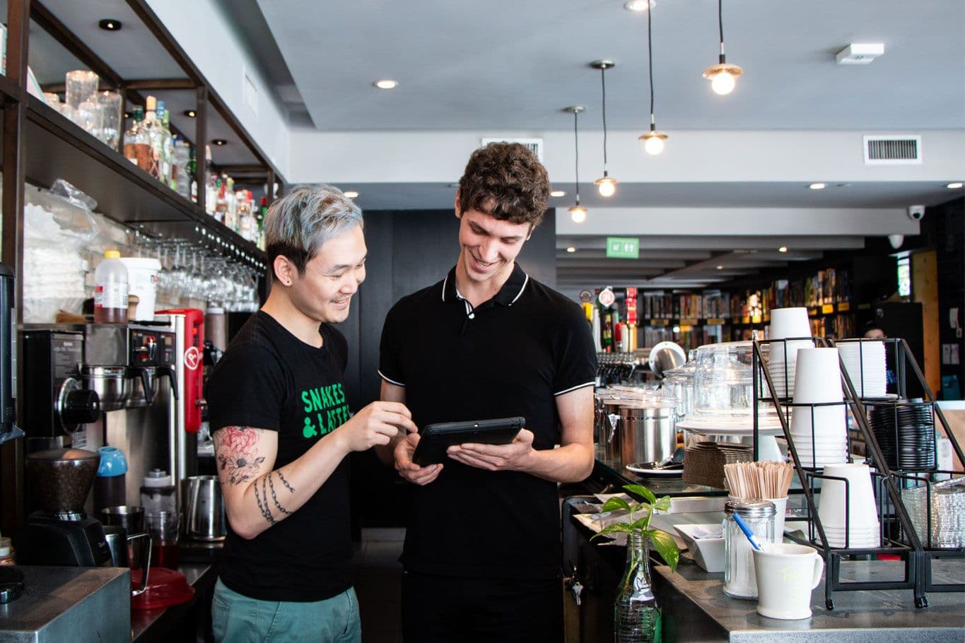 Baristas using tablet in coffee shop.