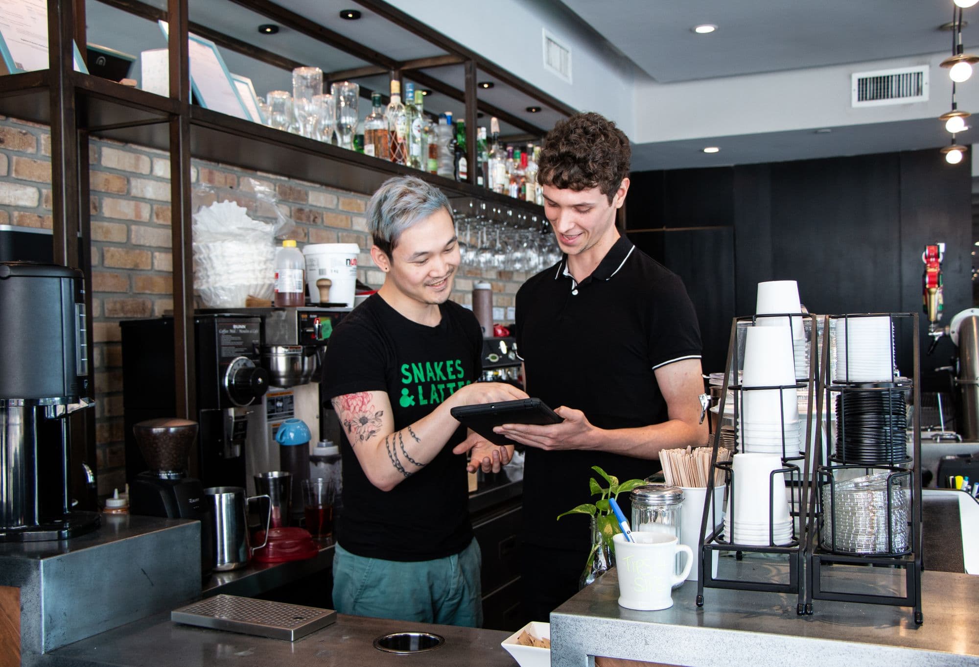 Baristas discussing cafe menu on tablet device.