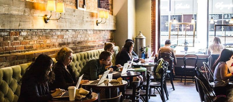 People work on laptops in cozy cafe.