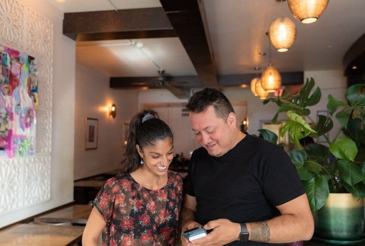 Two people smiling and looking at a phone.