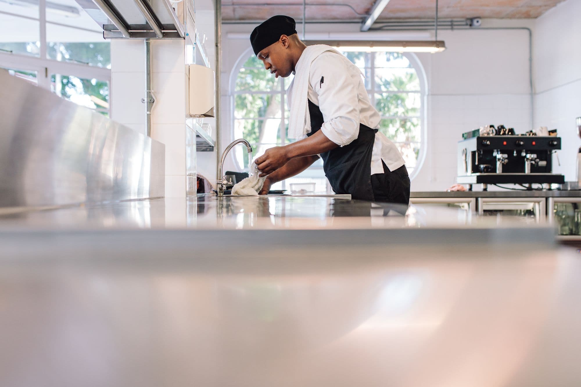 Chef washing dishes in a commercial kitchen.