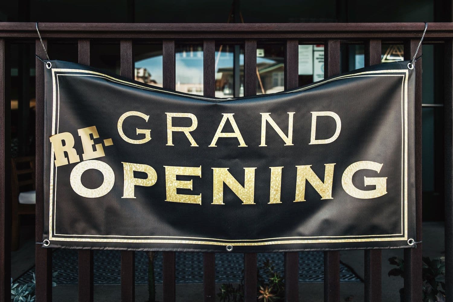 Re-grand opening banner sign on black background.