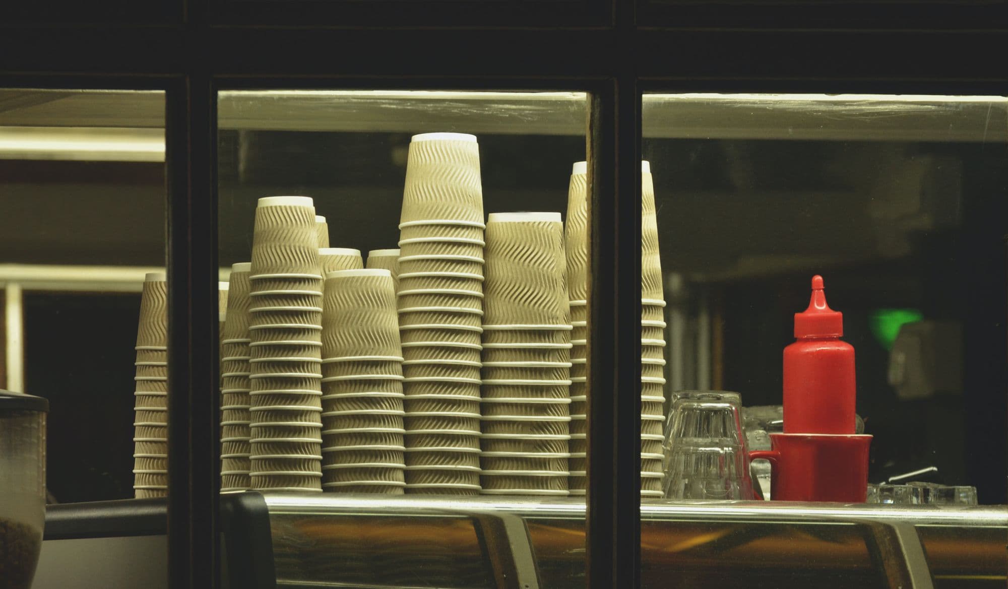 Stacks of paper cups and condiment bottle