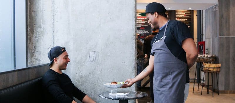 Waiter serving food to a seated customer.