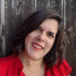 Smiling woman in red blouse against wooden background.
