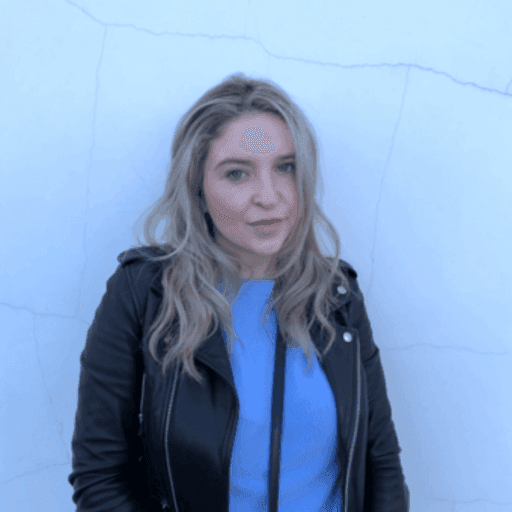 Woman in leather jacket against white wall.