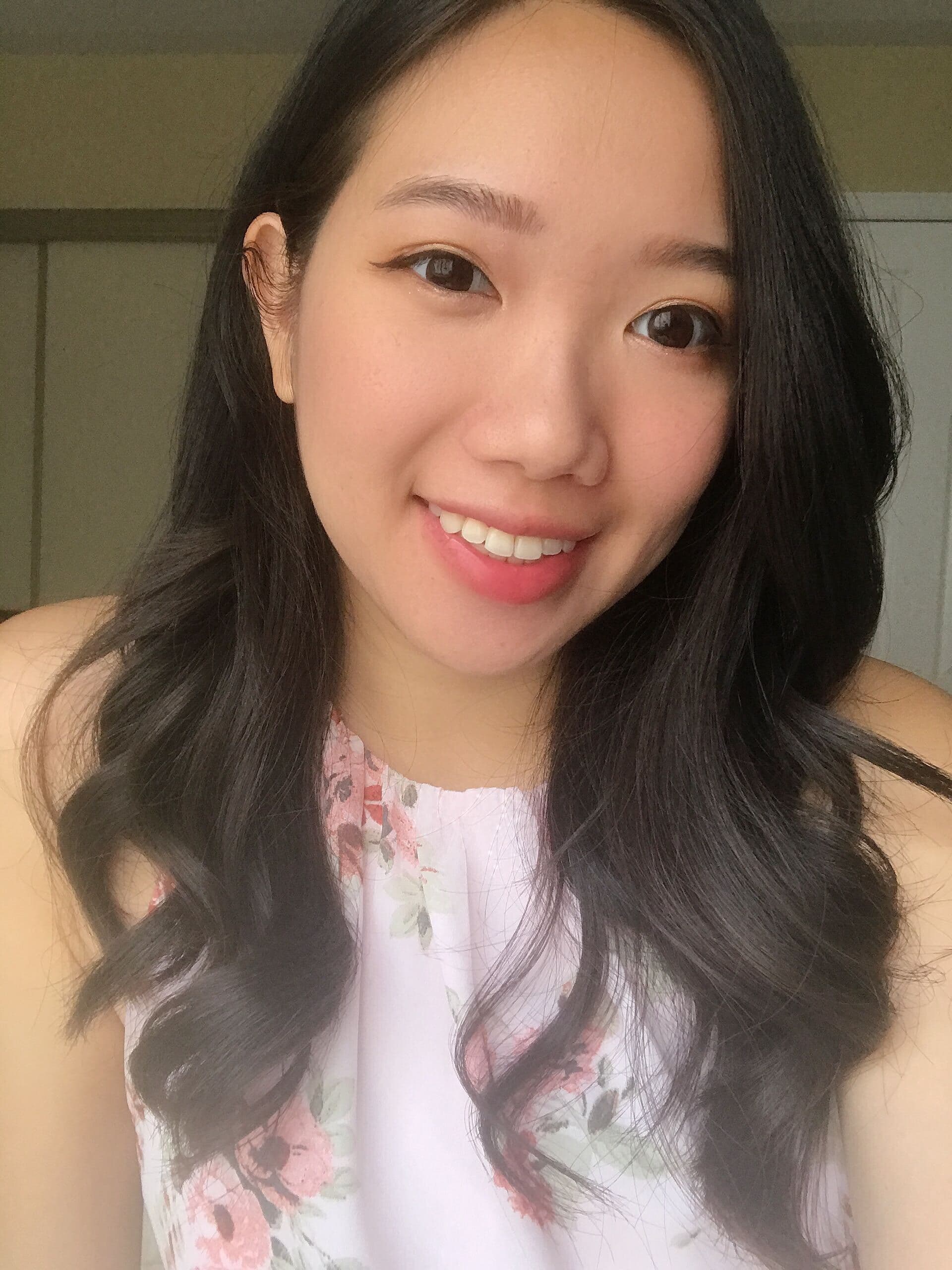 Woman smiling, wearing floral top, dark hair.