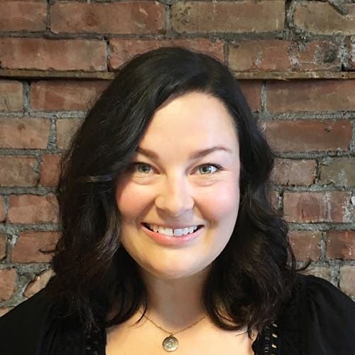 Smiling person in front of brick wall background.