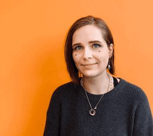 Person smiling in front of orange background