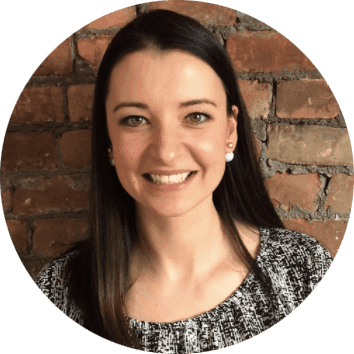 Smiling person in front of brick wall