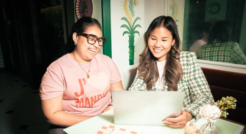 The regional manager and store manager at Mandy's Salads looking at the 7shifts app on a laptop and smiling