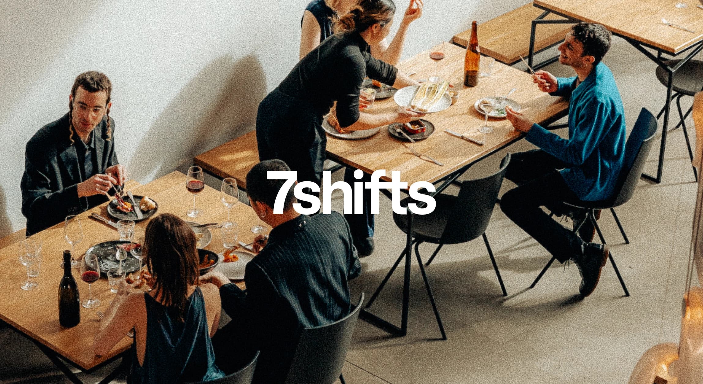 Waitstaff serving two groups of diners at a full service restaurant.