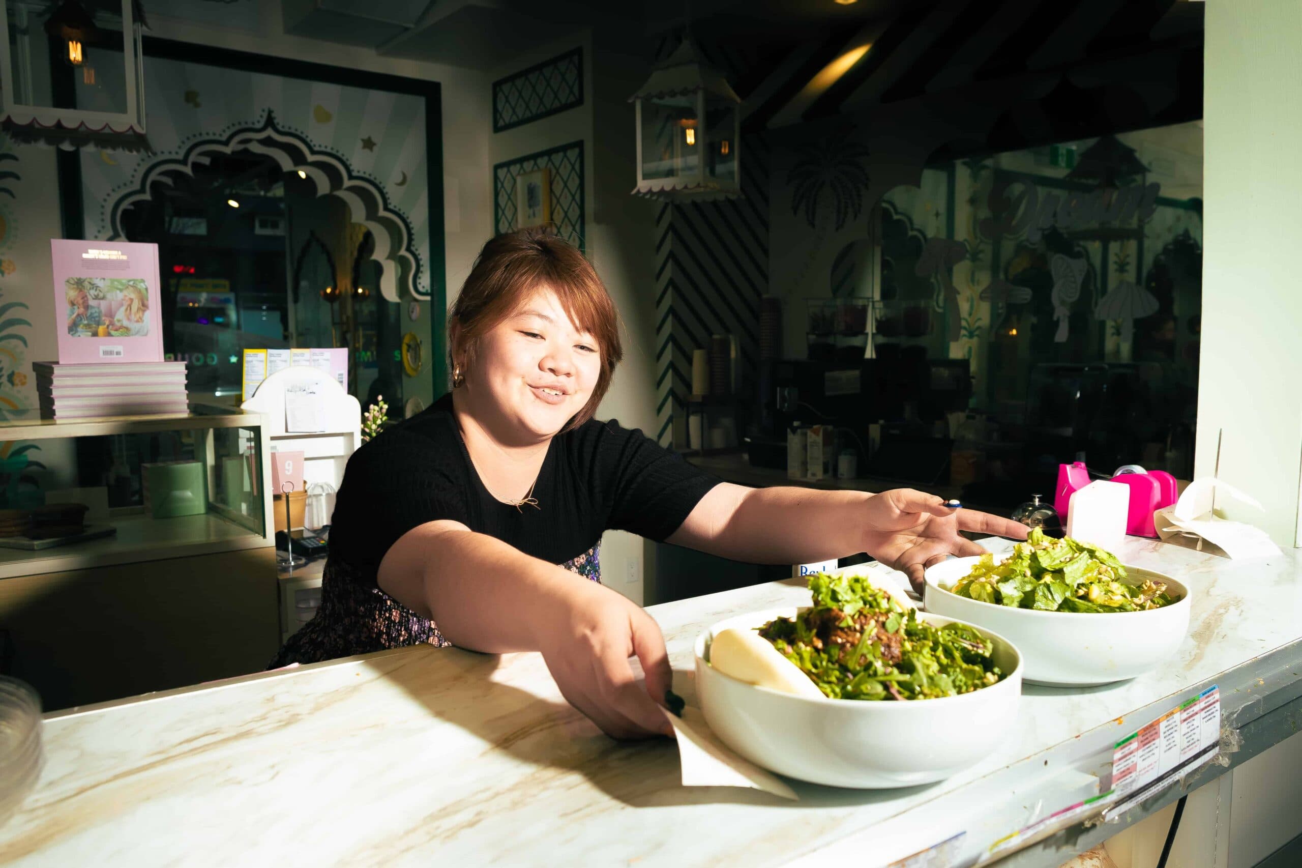 Woman serving salad bowls in a restaurant.