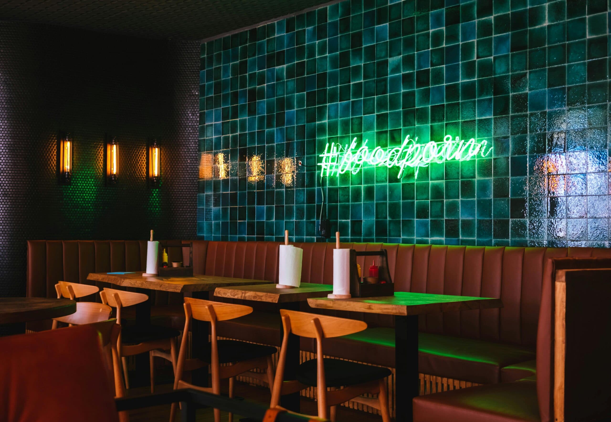 Stylish restaurant interior with neon sign and booths.
