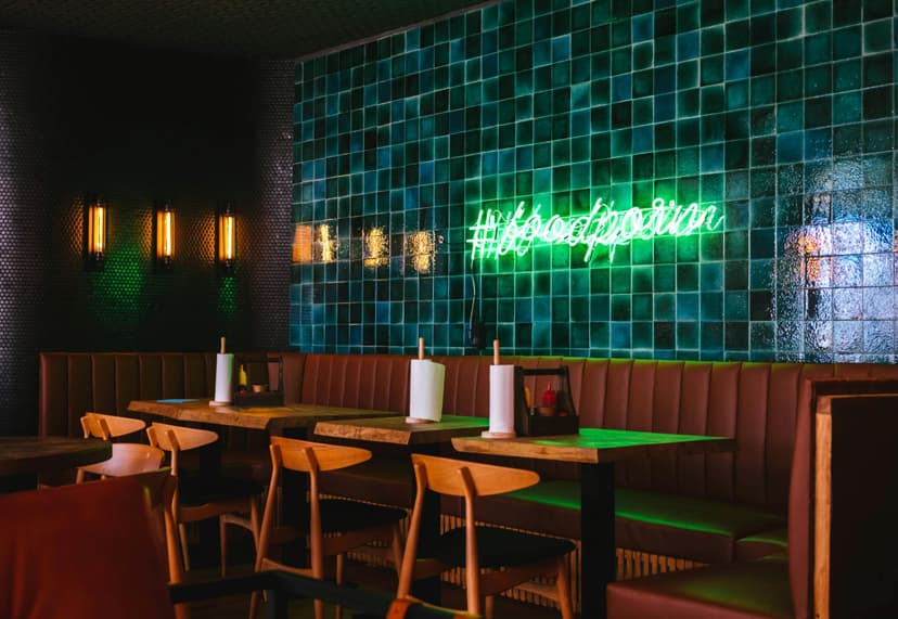 Stylish restaurant interior with neon sign and booths.