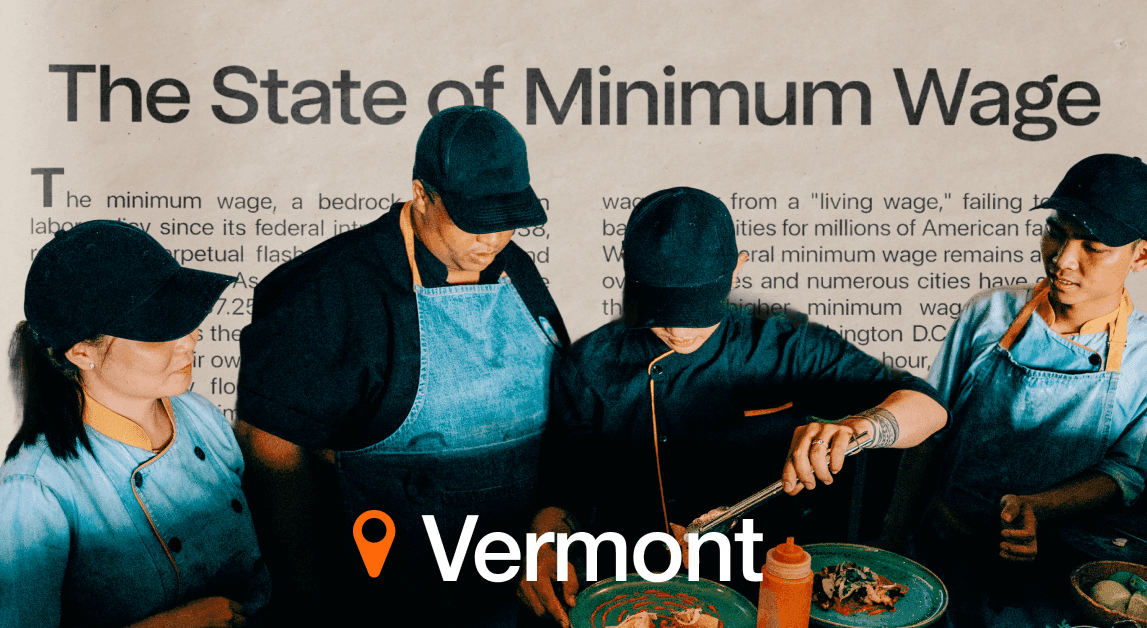 Workers prepare food under minimum wage sign, Vermont.