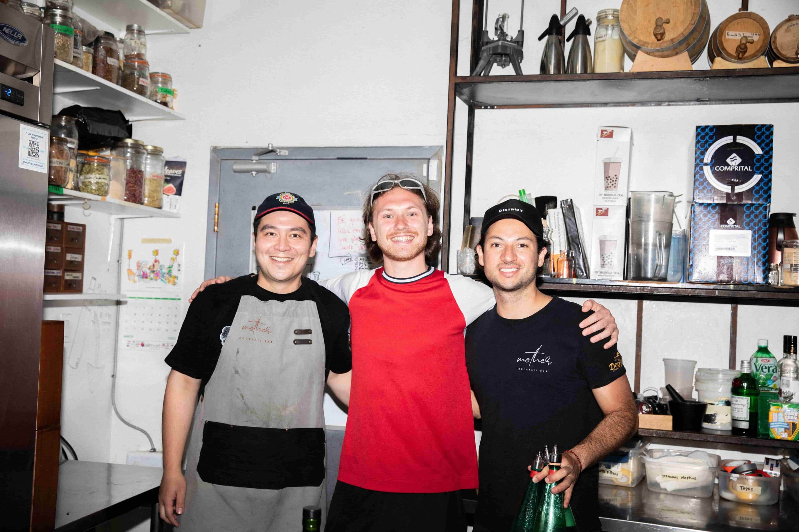 Three friends smiling in a kitchen.