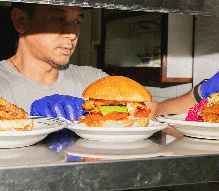 Chef plating gourmet burgers in restaurant kitchen.