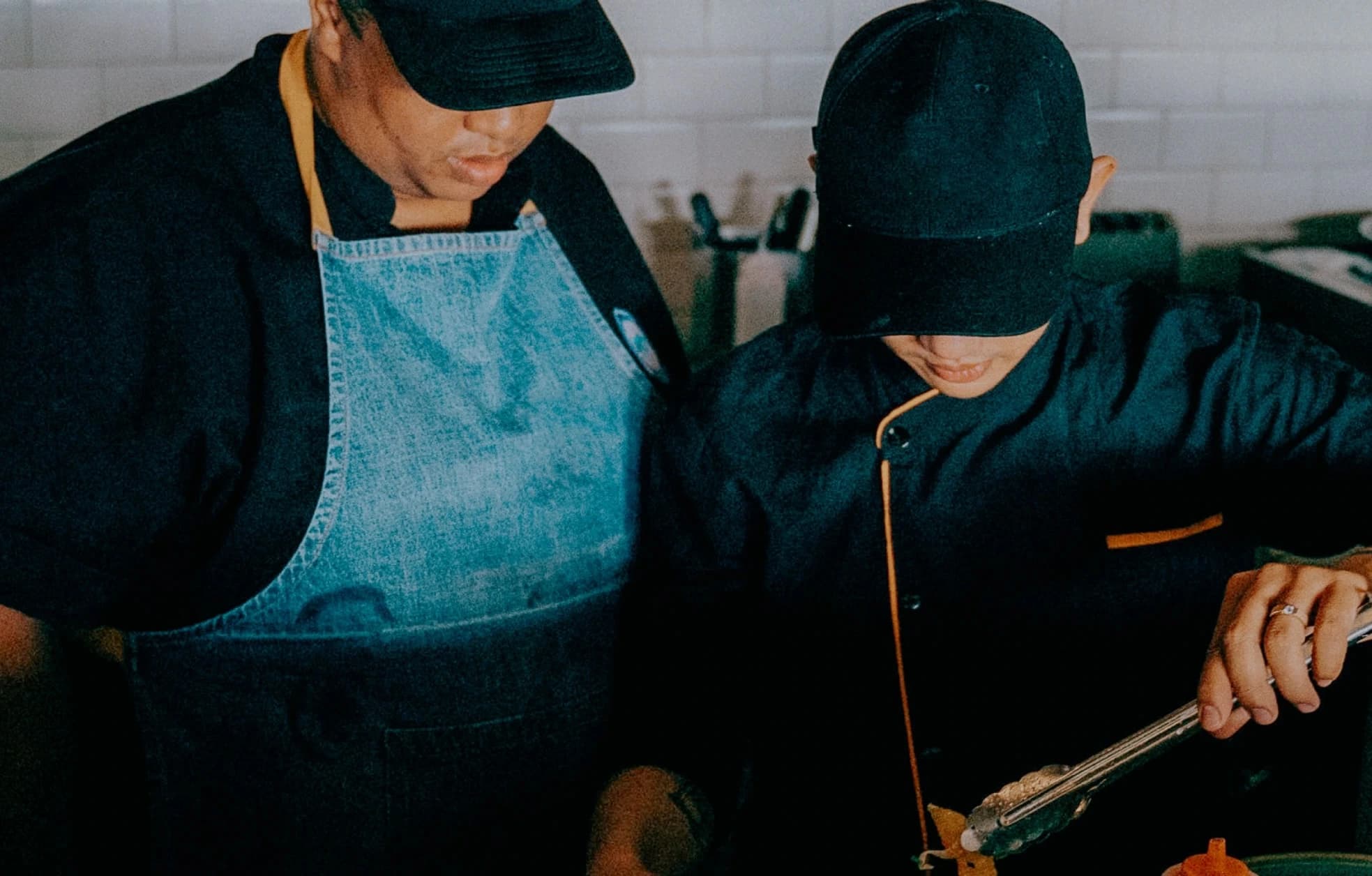 Two chefs preparing food in a kitchen.
