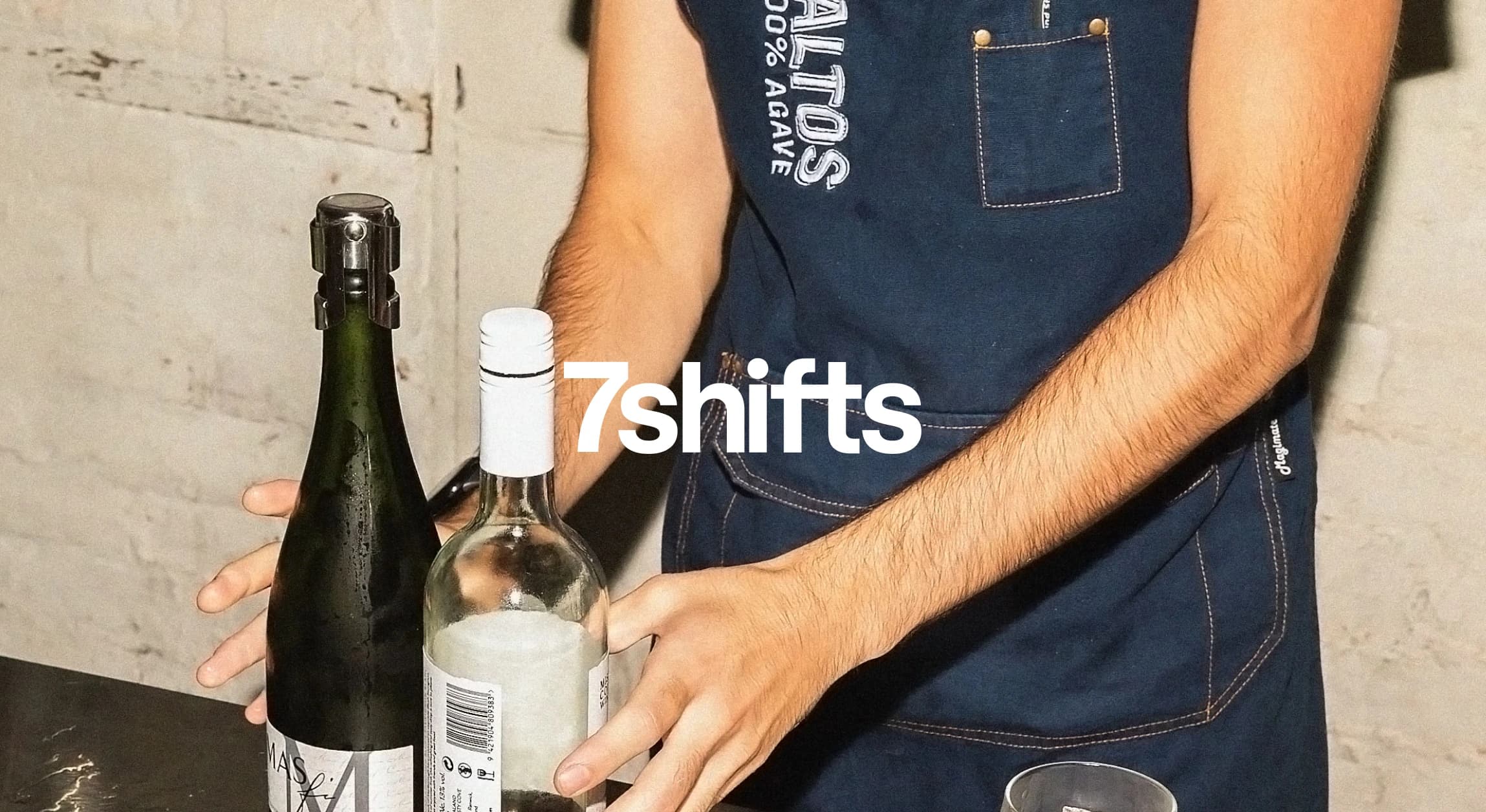 Person holding two bottles on counter.