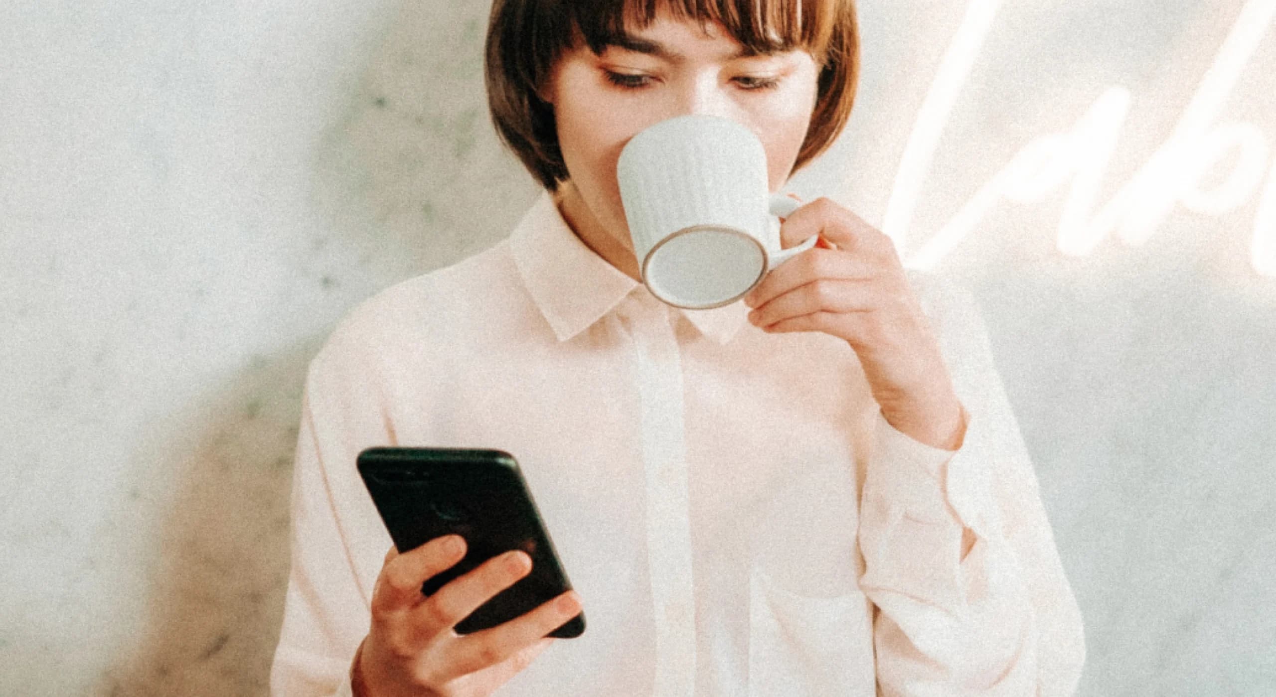 Woman drinking out of coffee cup while on phone