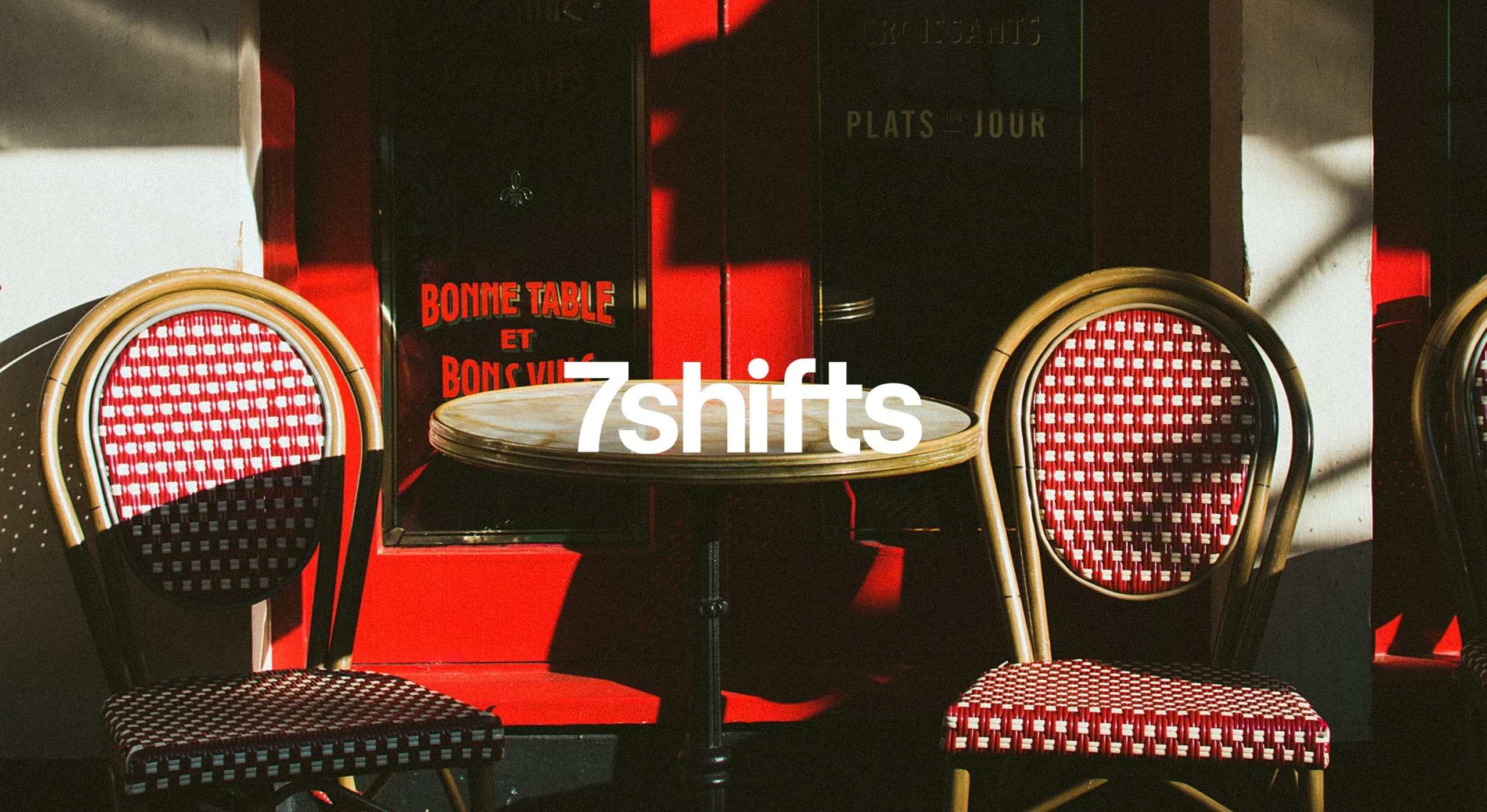 Two red chairs and a table in front of restaurant