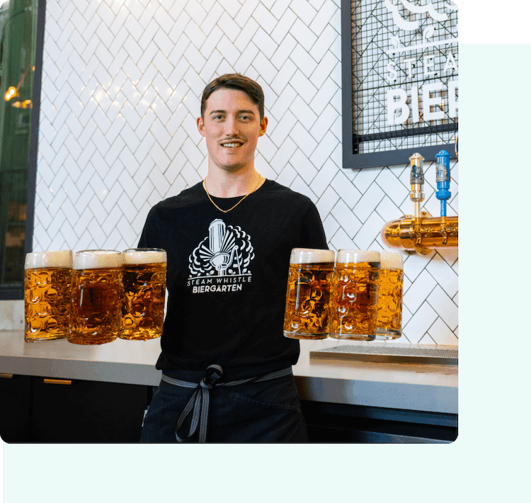 Steamwhistle Brewery employee smiling and holding 6 pints of beer